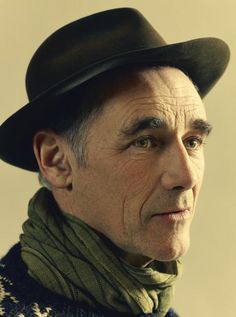 an older man wearing a black hat and green scarf looking off to the side with his eyes wide open