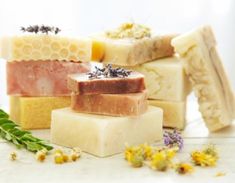 several soap bars with flowers and herbs on the side, all stacked up in front of each other