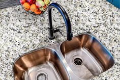 two stainless steel sinks in a kitchen with granite counter tops