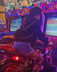 a woman riding on the back of a motorcycle in front of a video game machine