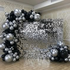 black and silver balloons are arranged in the shape of a happy new year's arch