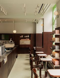 the interior of a restaurant with tables, chairs and shelves filled with books on them