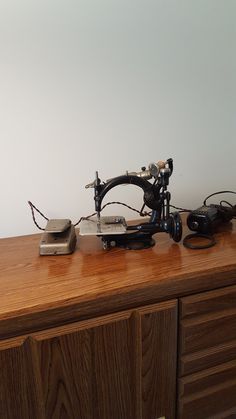 an old sewing machine sitting on top of a wooden dresser next to a phone charger