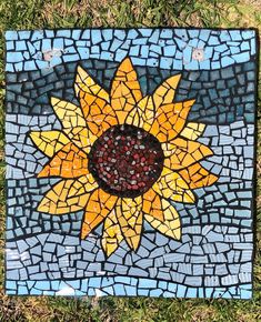 a mosaic sunflower on the ground with grass