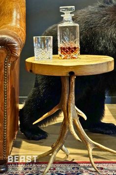 a bear sitting next to a table with two glasses on it