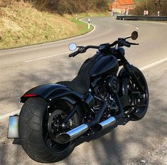 a black motorcycle parked on the side of a road next to a rural country road