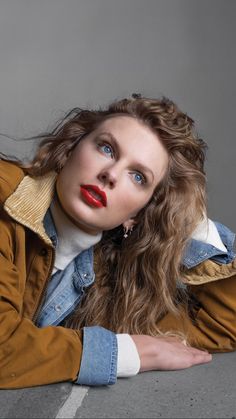 a woman laying on the ground with her hands behind her head and wearing a jacket