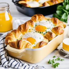 an egg and cheese casserole is shown on a table with orange juice in the background