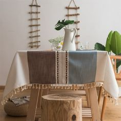 a table with a white vase on top of it next to a wooden stool and tree stump