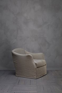 a white chair sitting on top of a hard wood floor next to a gray wall