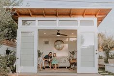 a man and woman sitting on a couch in the back of a garage with an open door