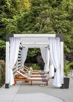 an outdoor gazebo with white curtains and wooden benches