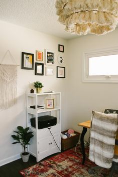 a room with a rug, table and pictures on the wall next to a window