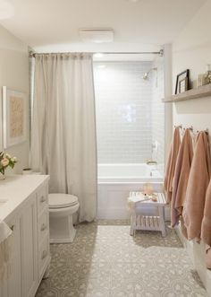 a white bathroom with beige towels hanging on the wall