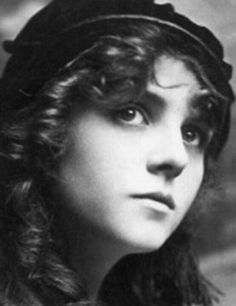 an old black and white photo of a woman with long hair wearing a beret