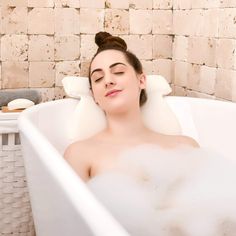 a woman laying in a bathtub with her eyes closed