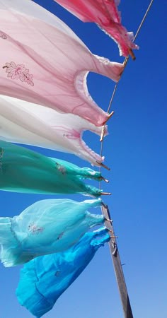 colorful flags blowing in the wind against a blue sky