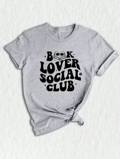 Introducing our exclusive Social Club Bookish T-Shirt, a must-have for all bookworms and avid readers! ✨ Perfect for book club enthusiasts and lovers of literature, this unique design merges style and intellect to create a statement piece for any occasion. Our social club shirt features a captivating illustration that brings together various elements of the bookish world.  The center focuses on a charming library, adorned with piles of books and a cozy reading chair. Surrounding it, adorable emojis depict the joy of reading, expressing your love for books without saying a word! ❤️ For those who are passionate about banned books or appreciate literary rebellions, this shirt showcases a subtle nod with a red "BANNED" stamp, adding an extra edge to your wardrobe.  Designed with comfort in min Book Club Shirts, Book Club Shirt, Book Lover Tshirt Design, Belles Book Club Shirt, Cozy Reading Chair, Cheap Bookish T-shirt With Funny Text, Bookworm Shirt, Book Club Meeting, Librarian Shirt