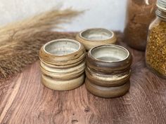 four wooden bowls sitting on top of a table next to some grain in a jar