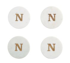 three white and gold coasters with the letter n on them