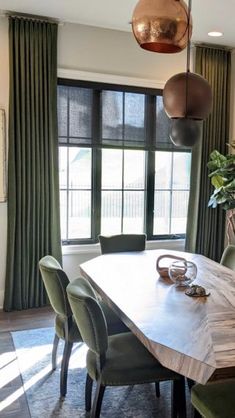 a dining room table with green chairs next to a window