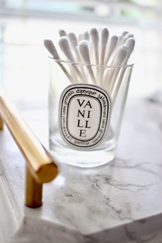 a glass filled with white matches sitting on top of a counter next to a wooden stick