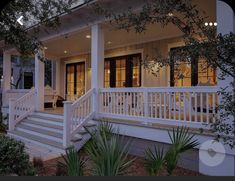 a white house with porches and stairs leading to the front door at night time