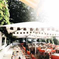 an outdoor dining area with tables, chairs and umbrellas set up for people to eat