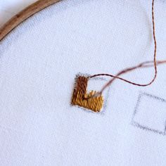 a close up of a cross stitch on a piece of cloth with a needle in it