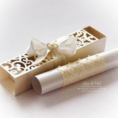 an open box with a white ribbon and bow on the top is sitting next to a roll of toilet paper