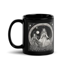 a black coffee mug with an image of two women sitting on the moon and stars