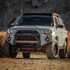 the front end of a white four - doored suv parked on a dirt road