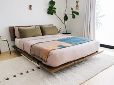 a bed sitting on top of a wooden platform next to a plant in a bedroom