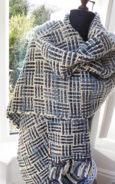 a blue and white plaid blanket draped over a mannequin