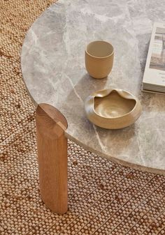 a coffee table with a book, bowl and cup on it