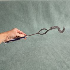 a person holding a pair of scissors in front of a piece of fabric that is shaped like a mustache