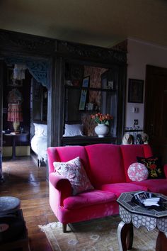 a living room with red couches and wooden floors in front of bookshelves