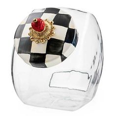 a black and white checkered glass vase with a red brooch on the top