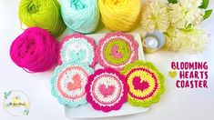 several balls of yarn sitting next to each other on a white surface with flowers in the background