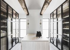 a kitchen with black and white cabinets and glass doors on the walls, along with wooden flooring