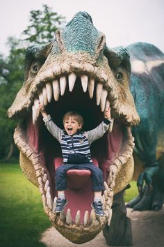 a young boy riding on the back of a fake dinosaur