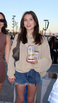 two women standing next to each other holding cans