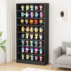 a book shelf filled with lots of cartoon figurines next to a gray couch