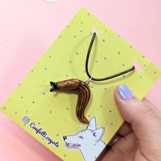 a hand holding a small card with a dog on it's back and a string attached to it