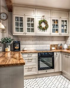 a kitchen with white cabinets and wood counter tops