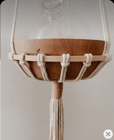 a wooden bowl with rope hanging from it's sides and a glass dome on top