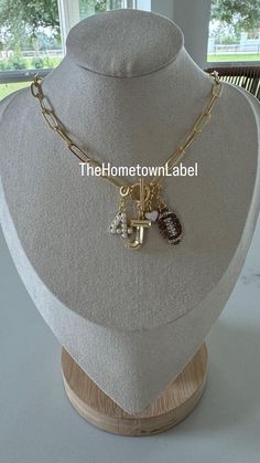 a necklace with charms on it sitting on a mannequin head stand in front of a window