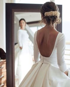 the back of a woman's dress is shown in front of a mirror and another woman