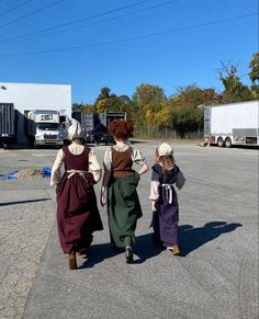 three women in period clothing walking down the street together, one carrying a child's hand