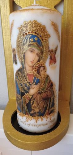 a candle with an image of the virgin mary and child jesus in gold trimming